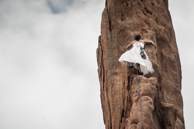Woman climbing mountain in wedding dress