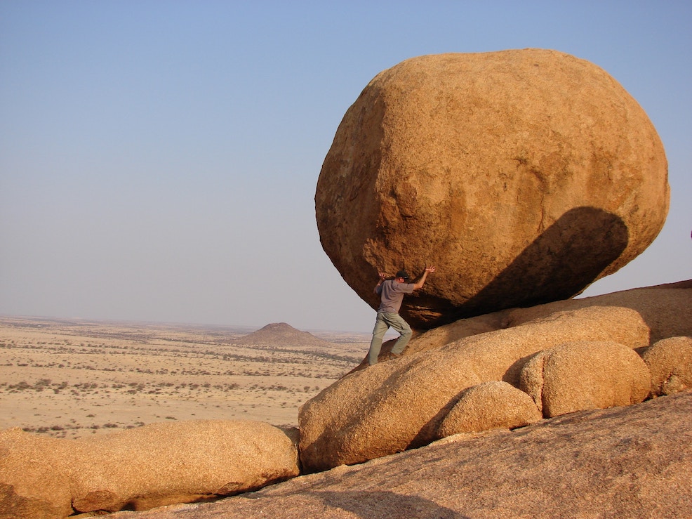 Man pushing huge boulder