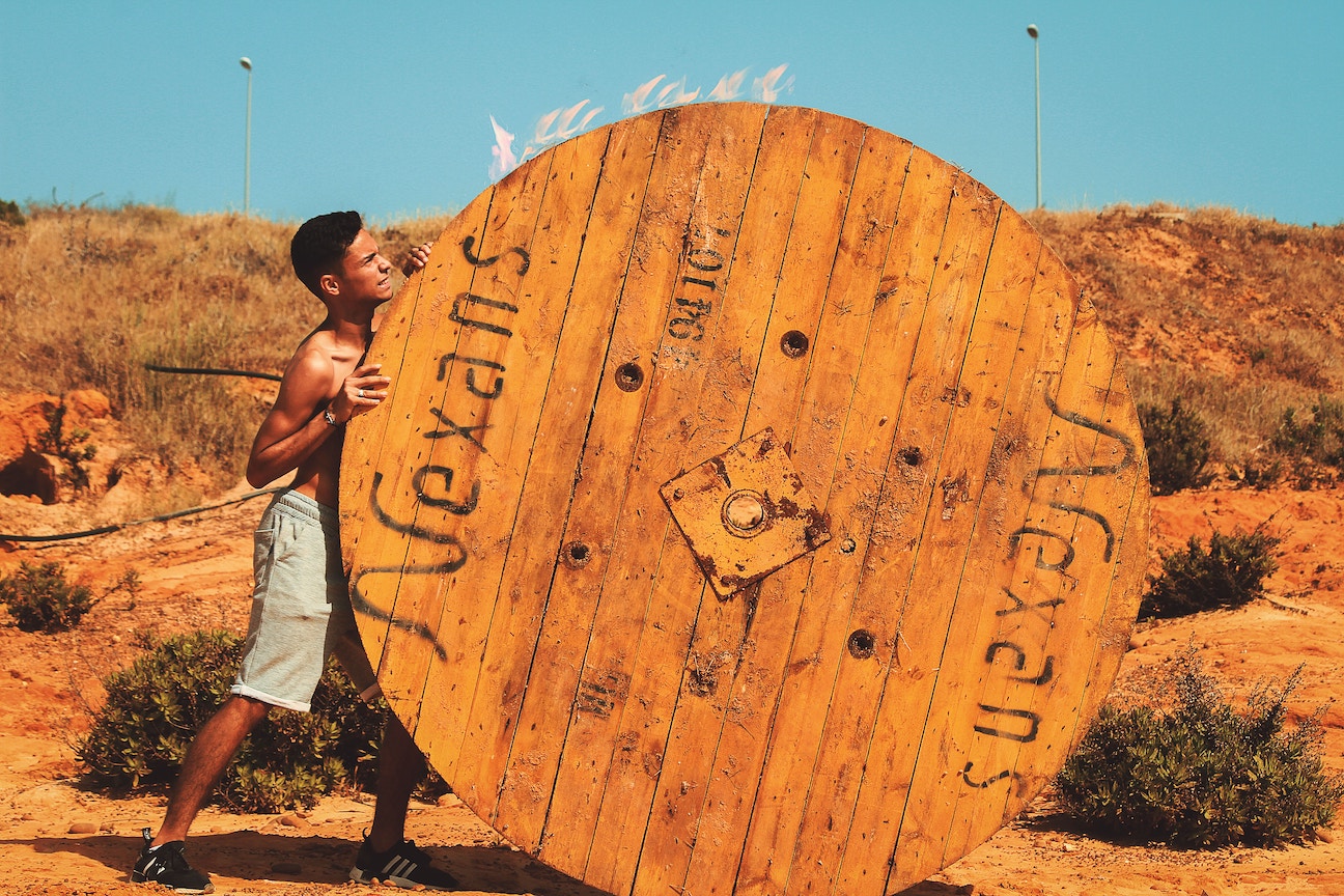 Man pushing big wooden wheel