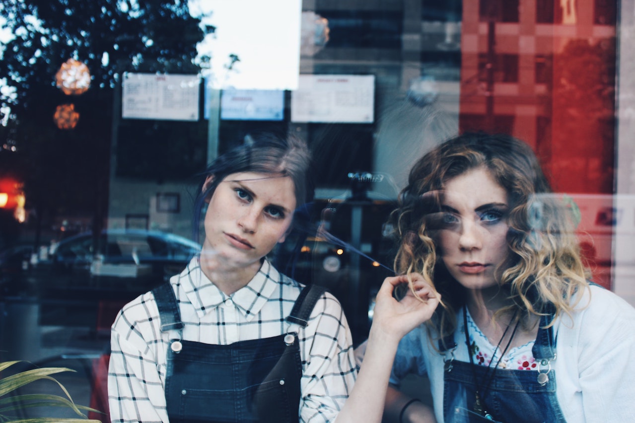 Two girls in dungarees looking bored