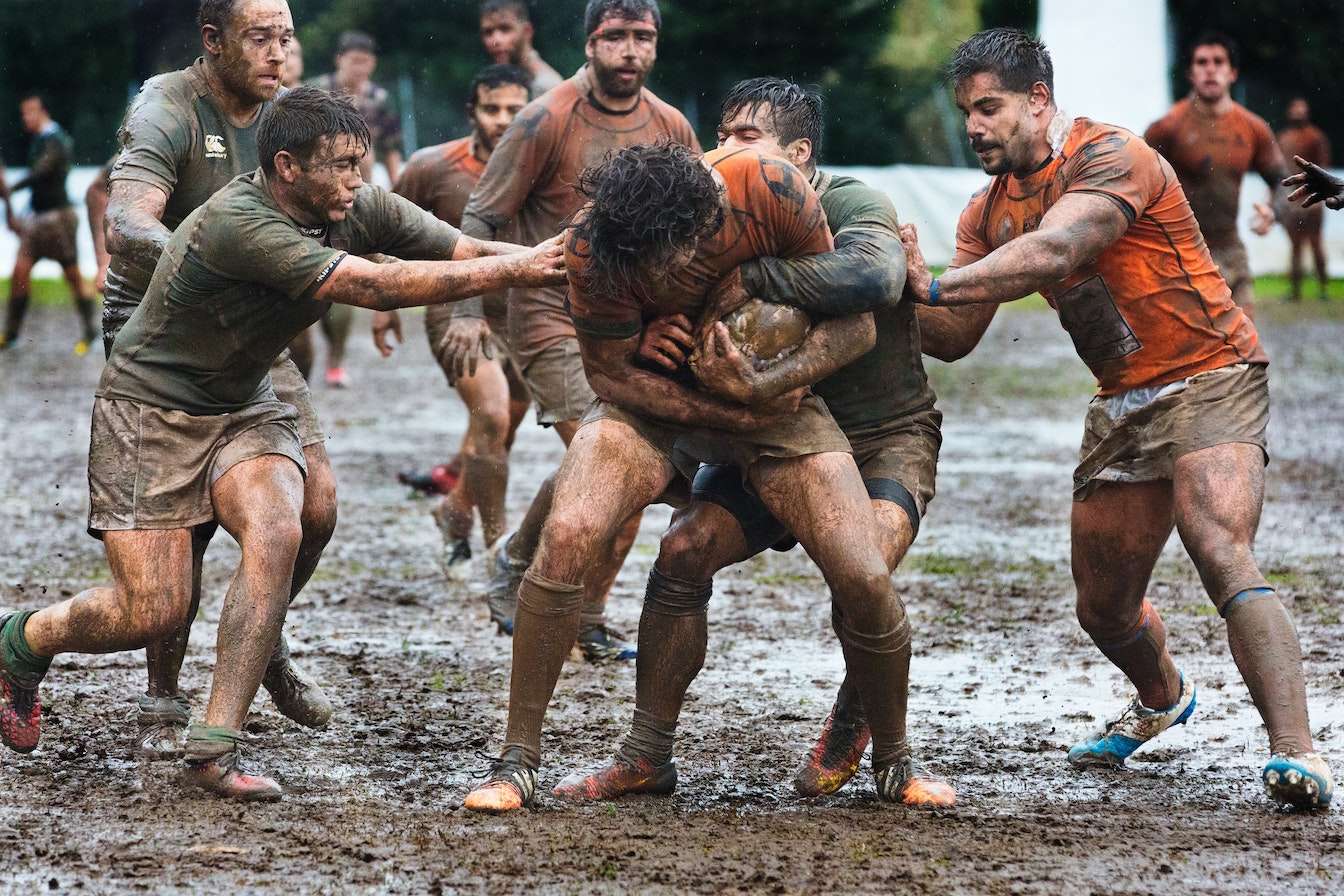 Men playing rugby in mud