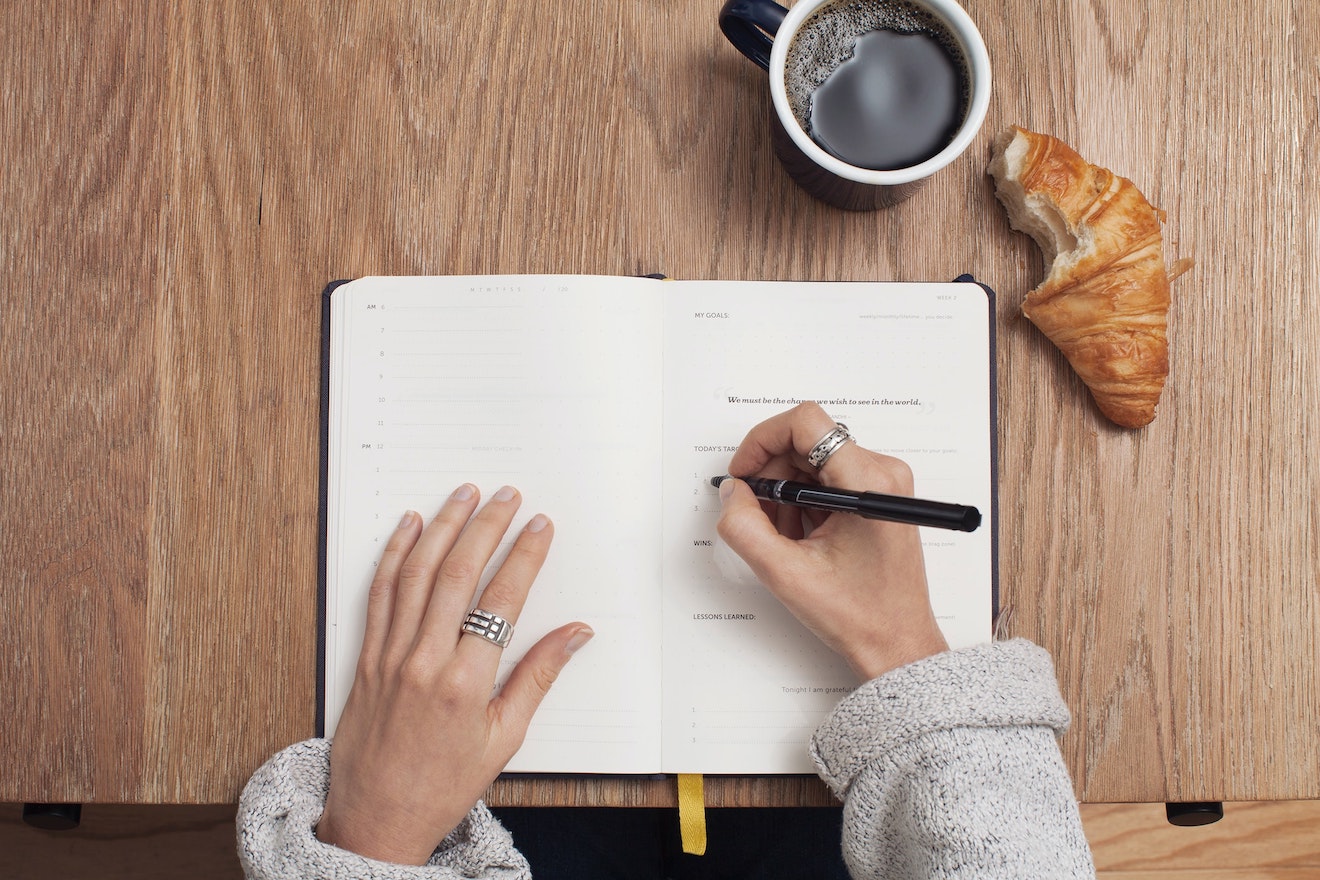 Hands writing in a book on a table