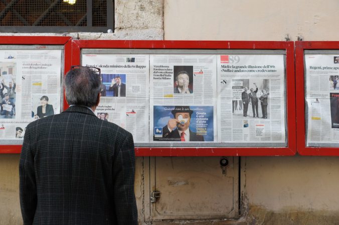 Man staring at a bunch of newspapers