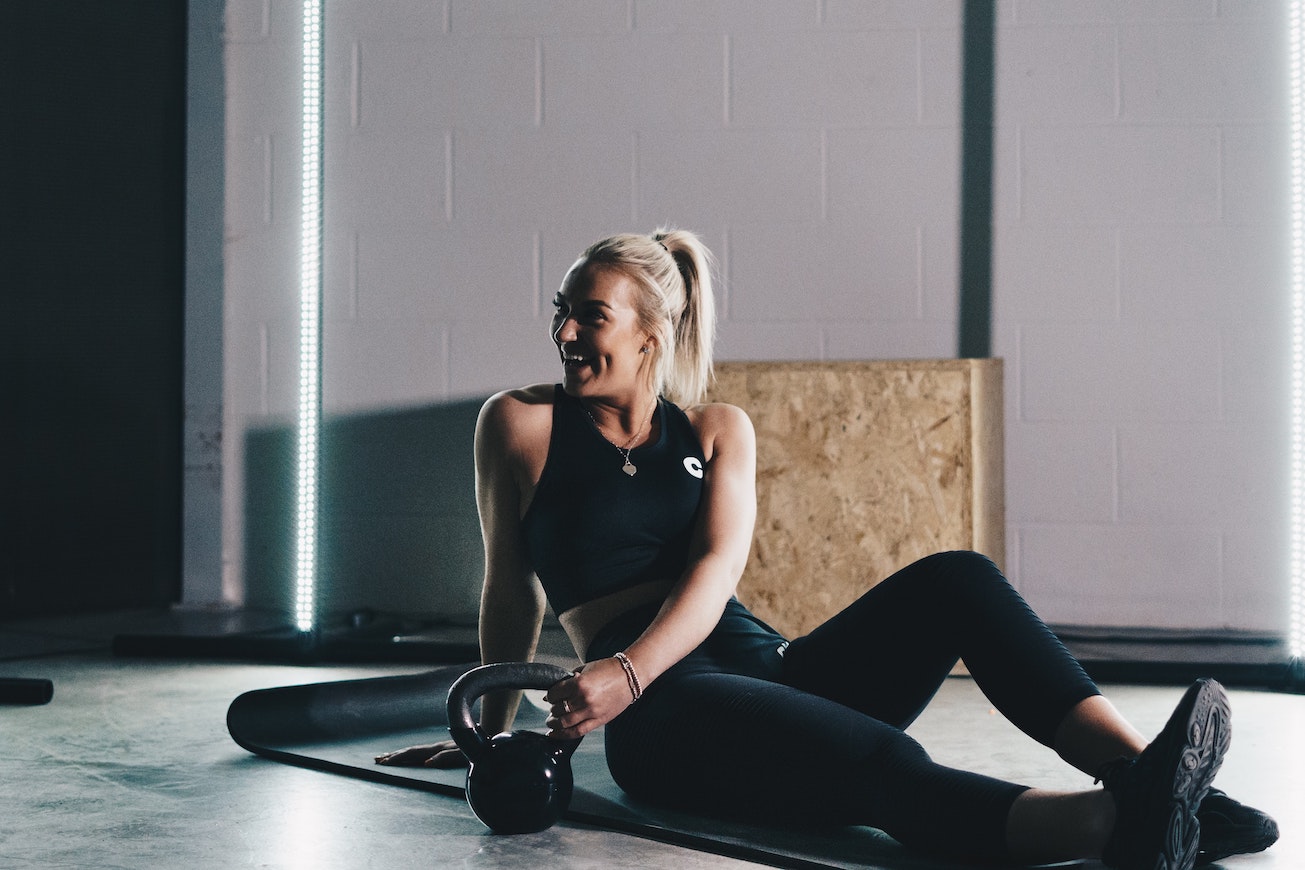 Woman in sportswear sitting next to kettlebell