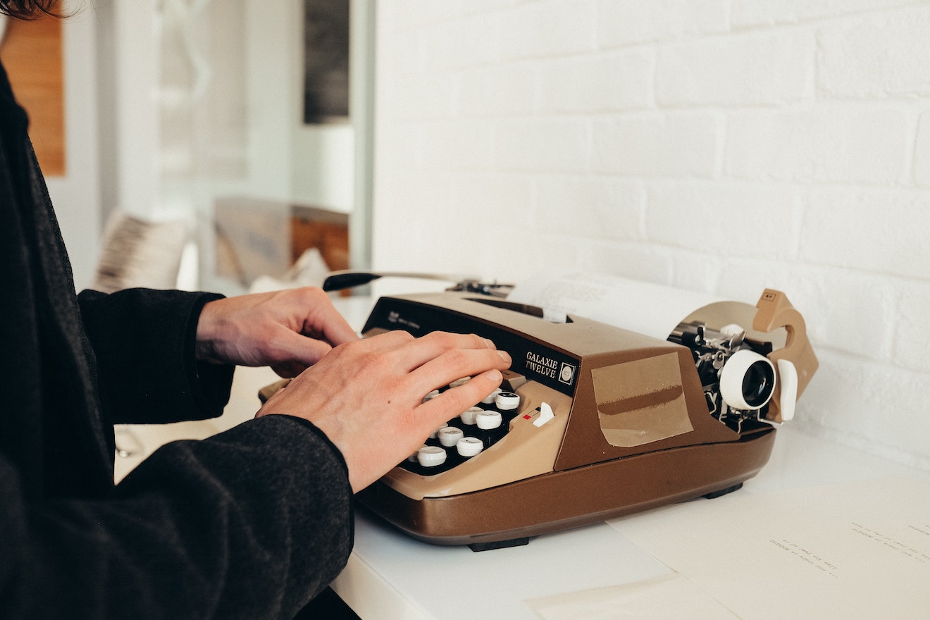Someone typing on a brown classic typewriter