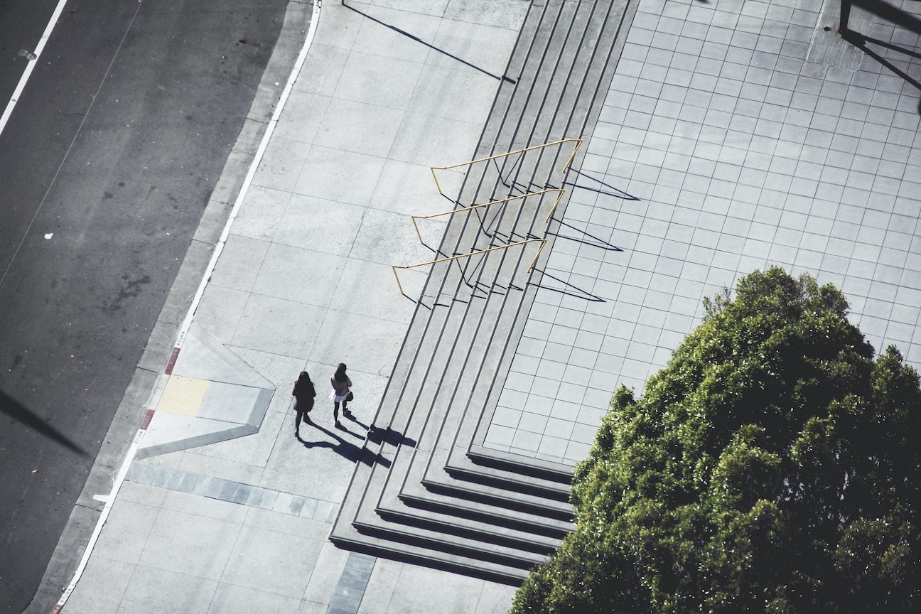 Two women walking down a street with stairs, from a bird's-eye view