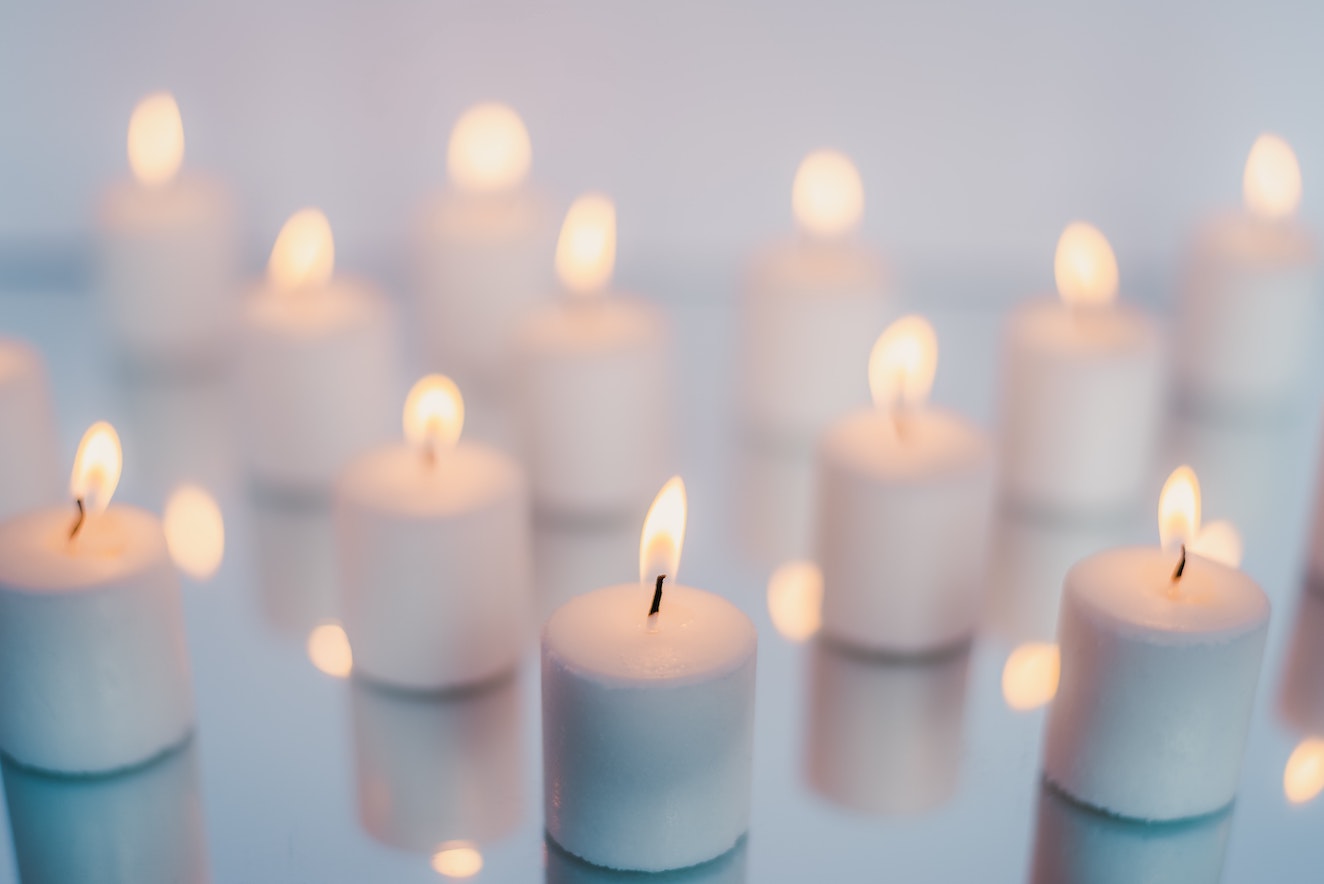 A bunch of white candles that are lit