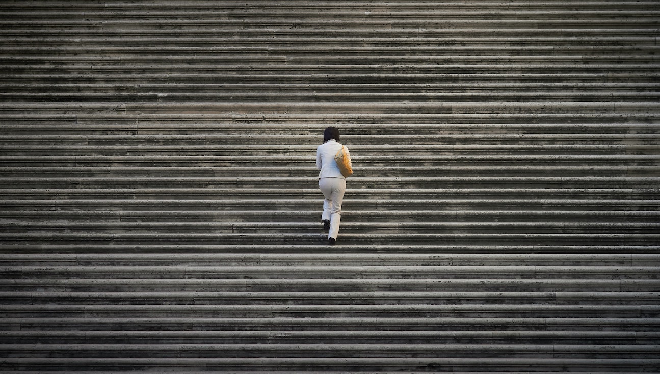 Woman in grey clothes walking up many grey steps