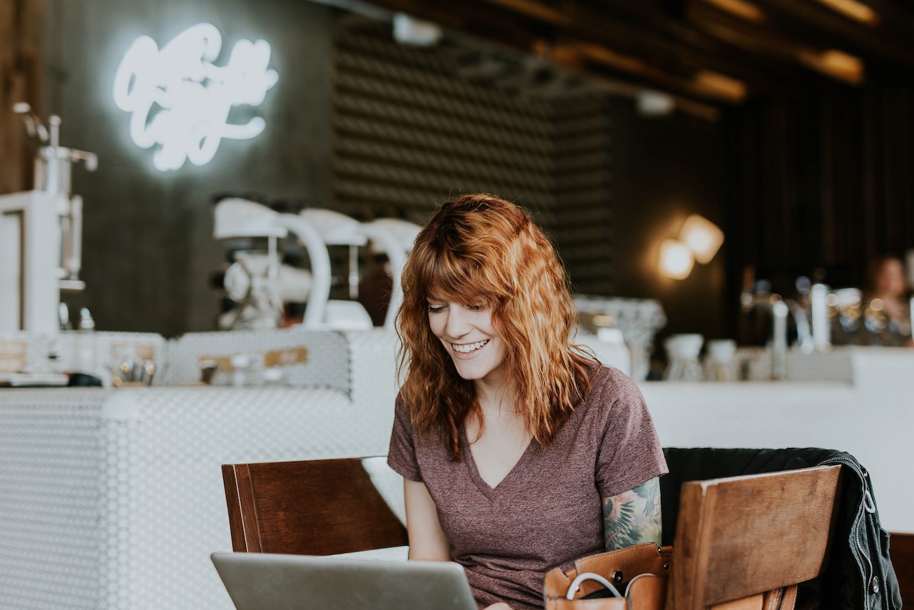 A redheaded woman at a cafe with her laptop