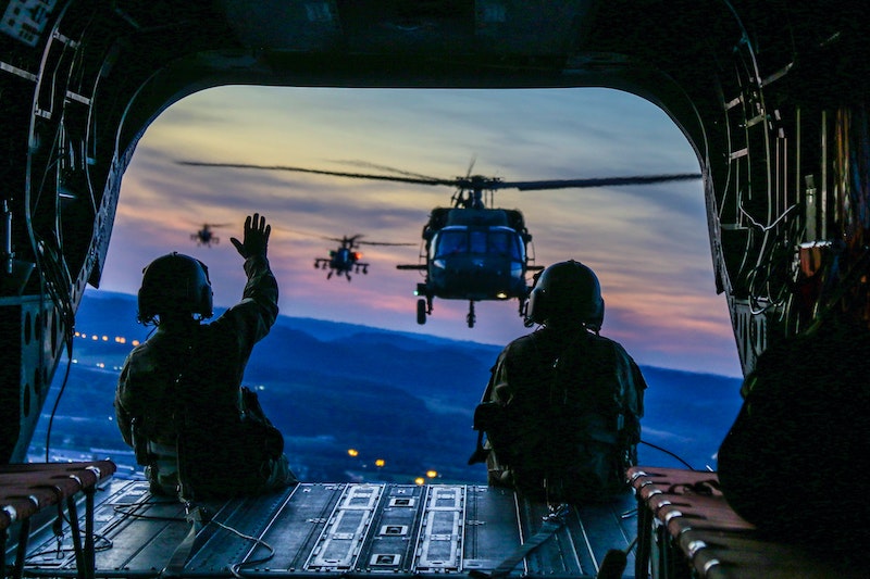 Two army guys sitting in a helicopter