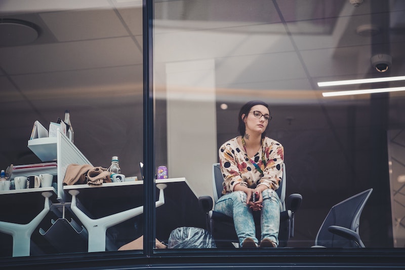 A woman in glasses staring out the window with a bored look