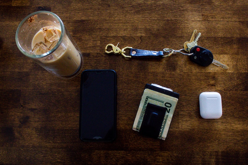 Wallet, phone, and keys on a wooden desk