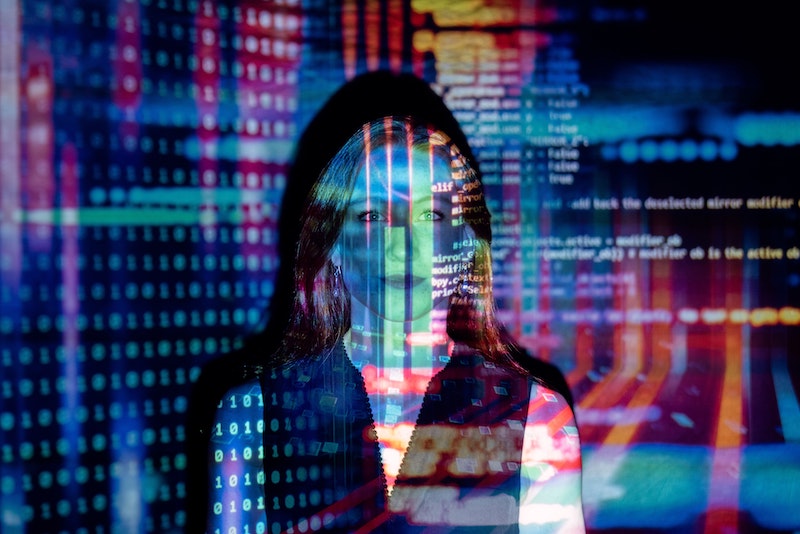 Woman standing in front of projector with lines of code on her face