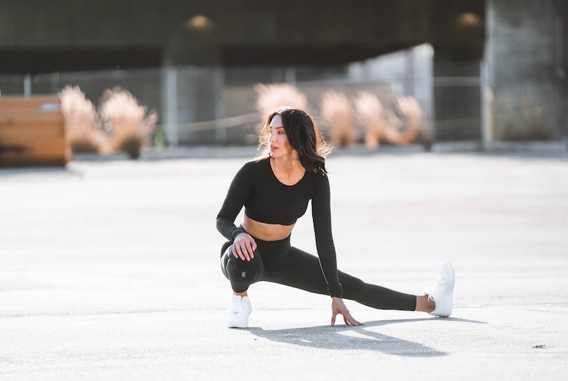 A woman in athletic wear stretching in a cossack squat