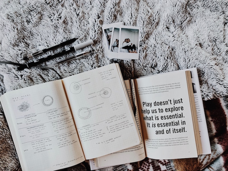 Flat lay of a journal, a book, polaroid photos, and stationery