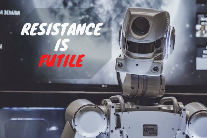 A mean-looking robot in front of a screen. Words on pic says 'resistance is futile'